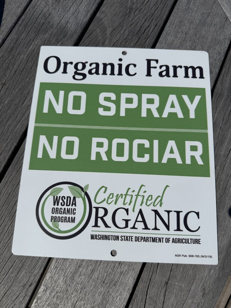 WSDA Certified Organic sign reading Organic Farm No Spray No Rociar from the Washington State Department of Agriculture organic program